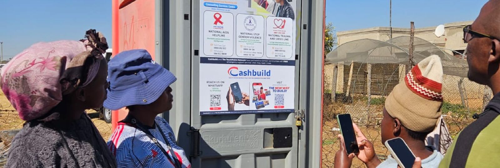 Community members scanning a TouchPoiint Network poster with their phones at a sanitation hub